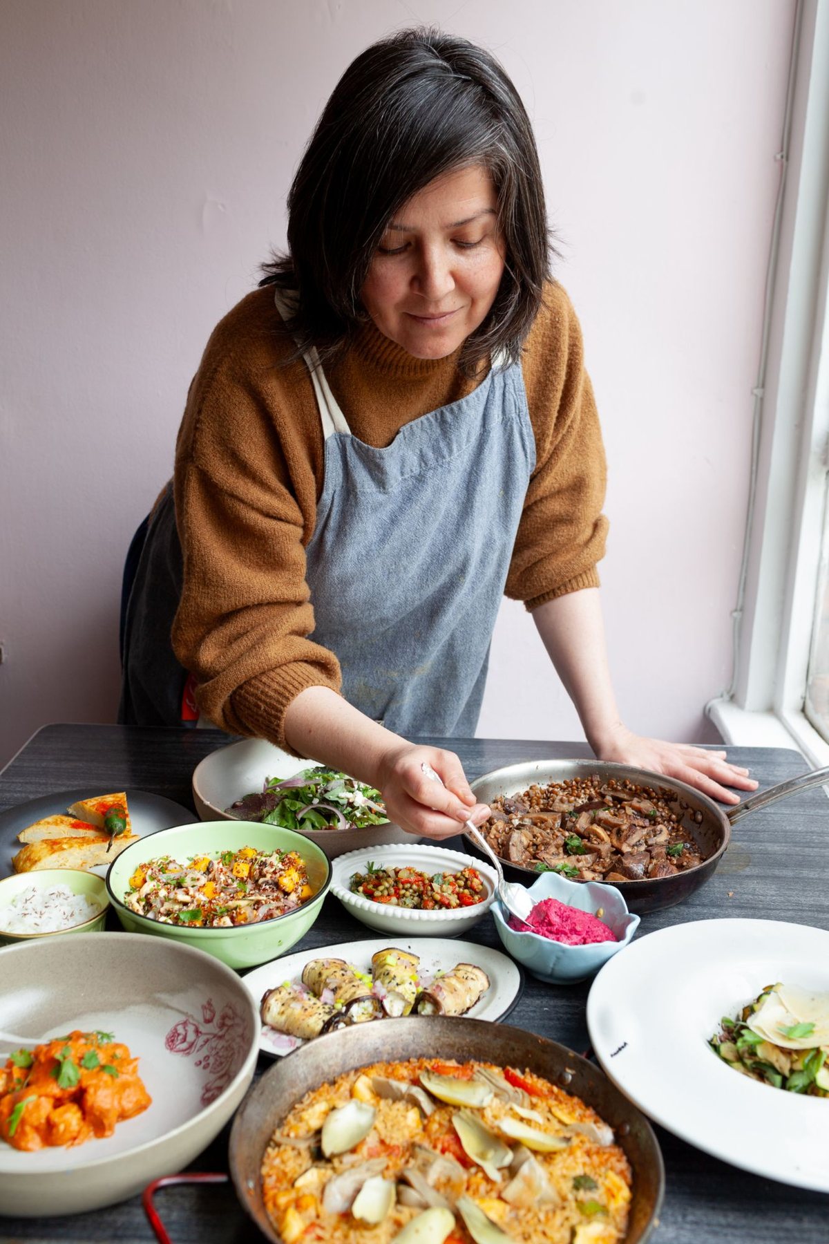 Diana González sirviendo una mesa de preparaciones de su cocina