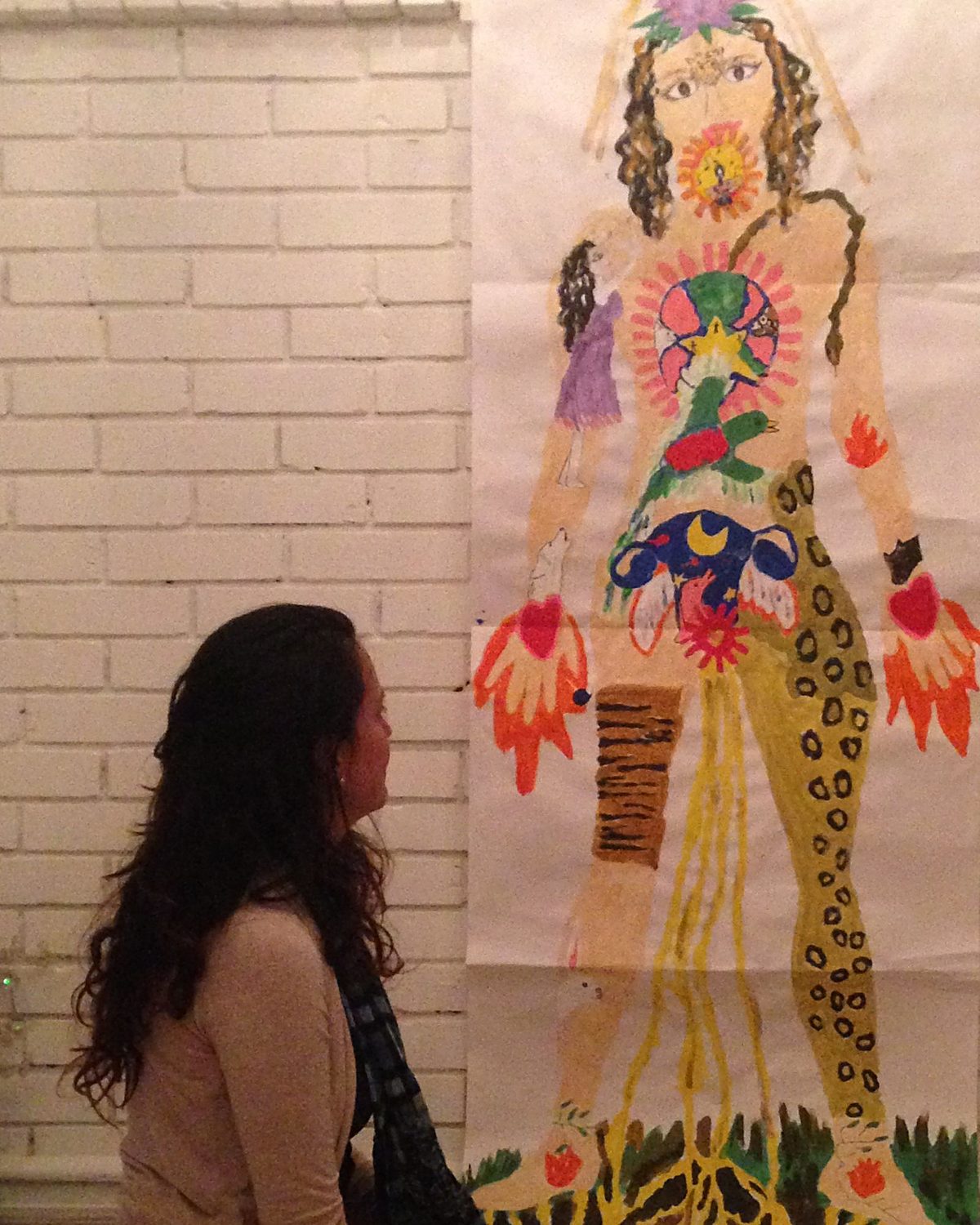 Una mujer mira el dibujo de su cuerpo en un proceso de artes expresivas Tamalpa
